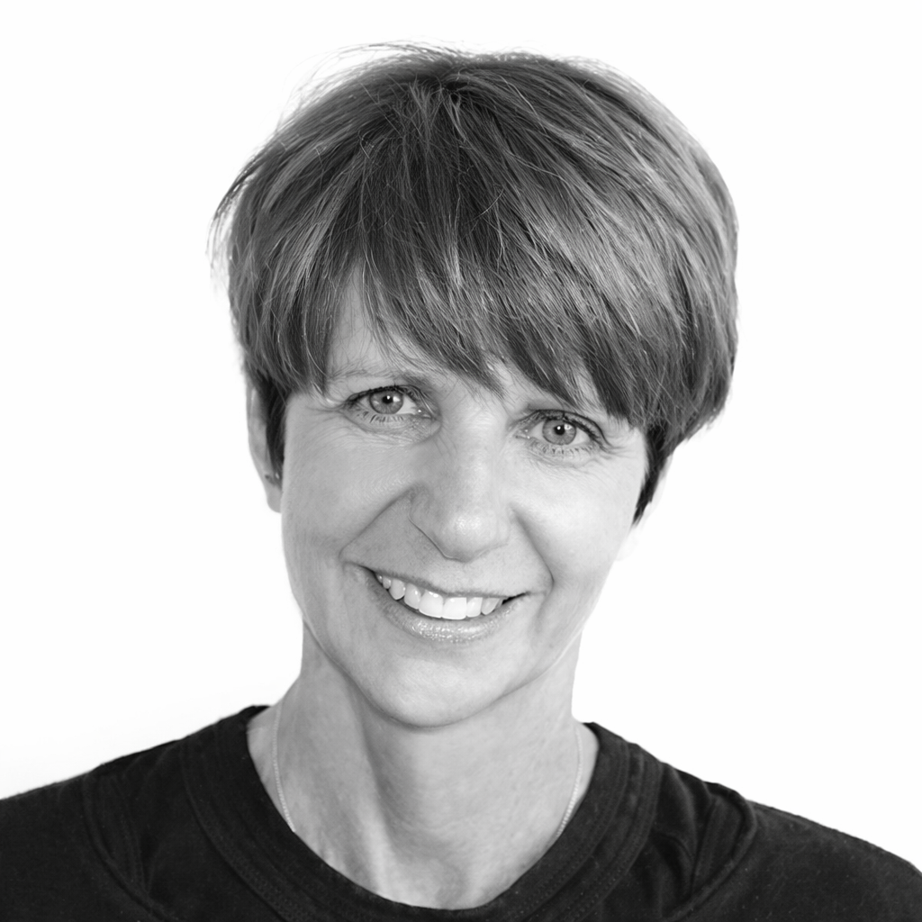Black and white portrait of a smiling woman with short hair wearing a black top.