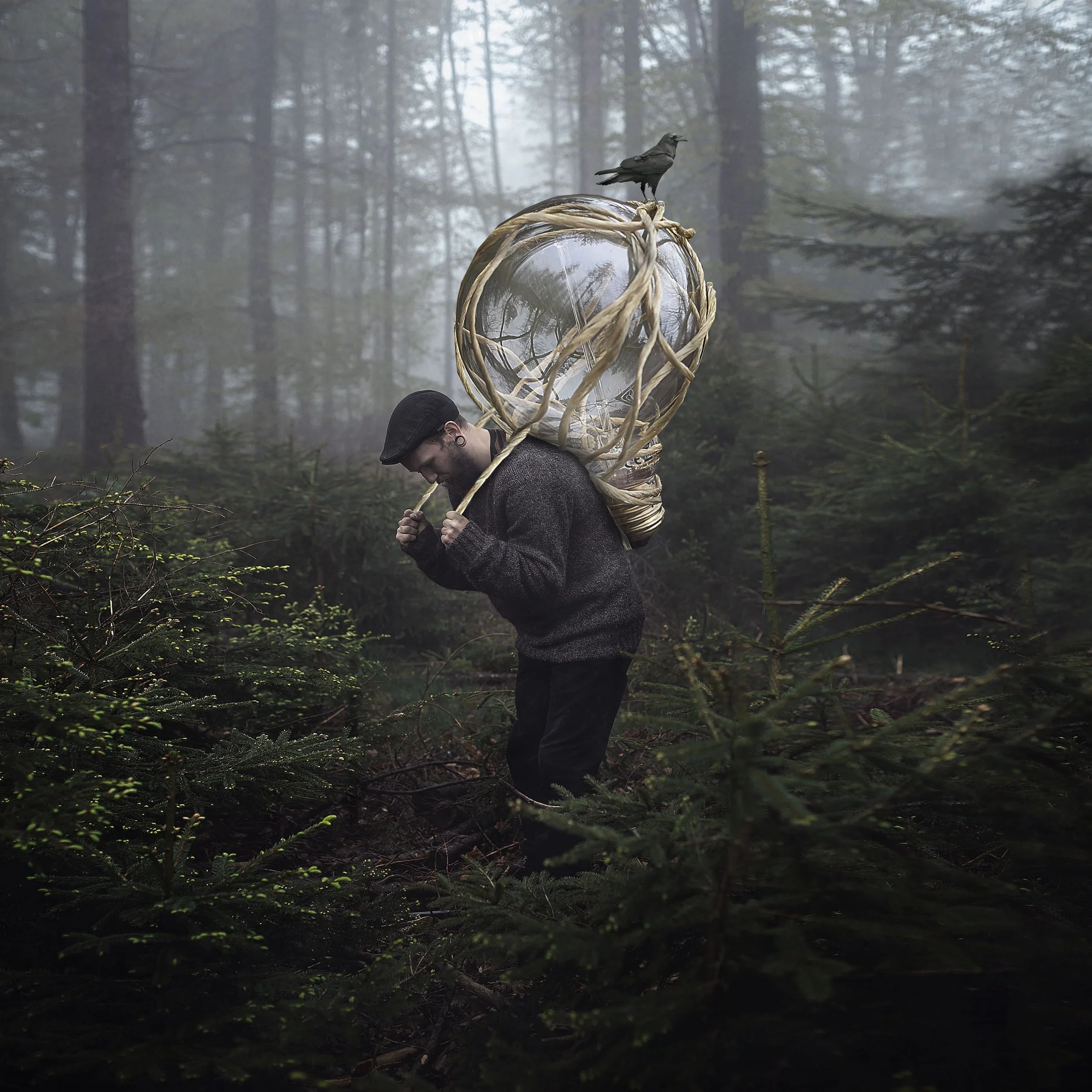 Ein Mann trägt eine große, schilfartige Laterne auf seinem Rücken, während er durch einen nebligen Wald wandert; ein Rabe sitzt auf der Laterne.