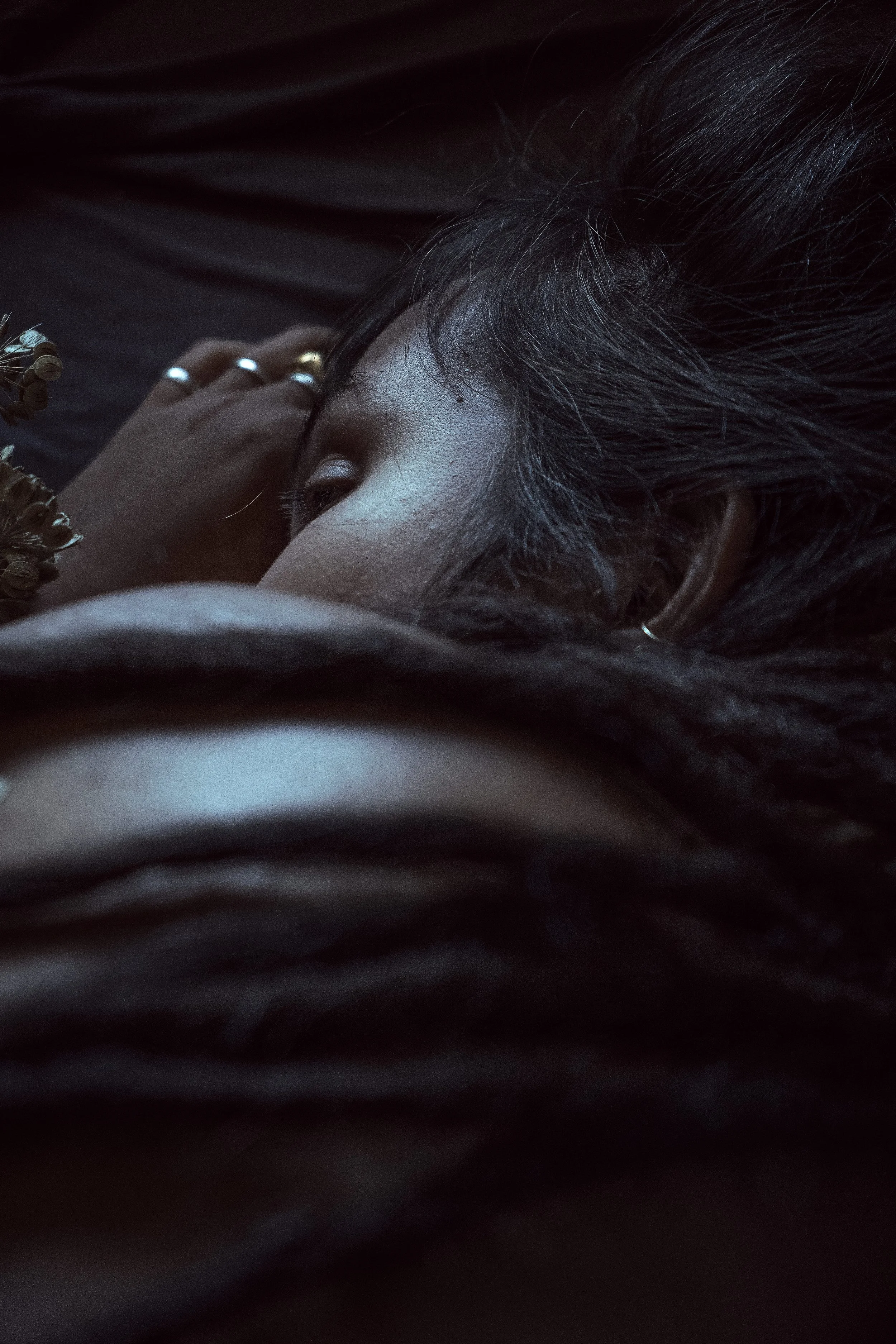 Nahaufnahme eines Menschen mit dunkler Haut und schwarzen Haaren, liegend und mit geschlossener Auge, in einer dunklen Umgebung.