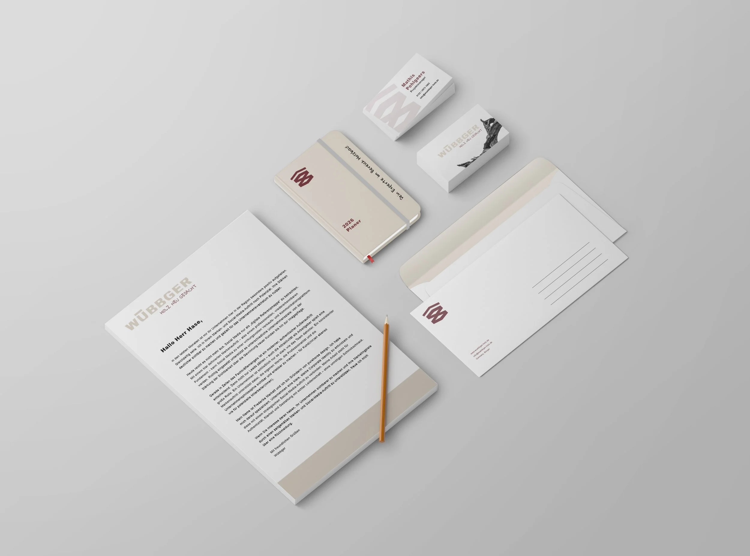 Collection of stationery on a gray surface, including letters, envelopes, business cards, a planner, and a pen, all branded with WUBUBGER logo and text.