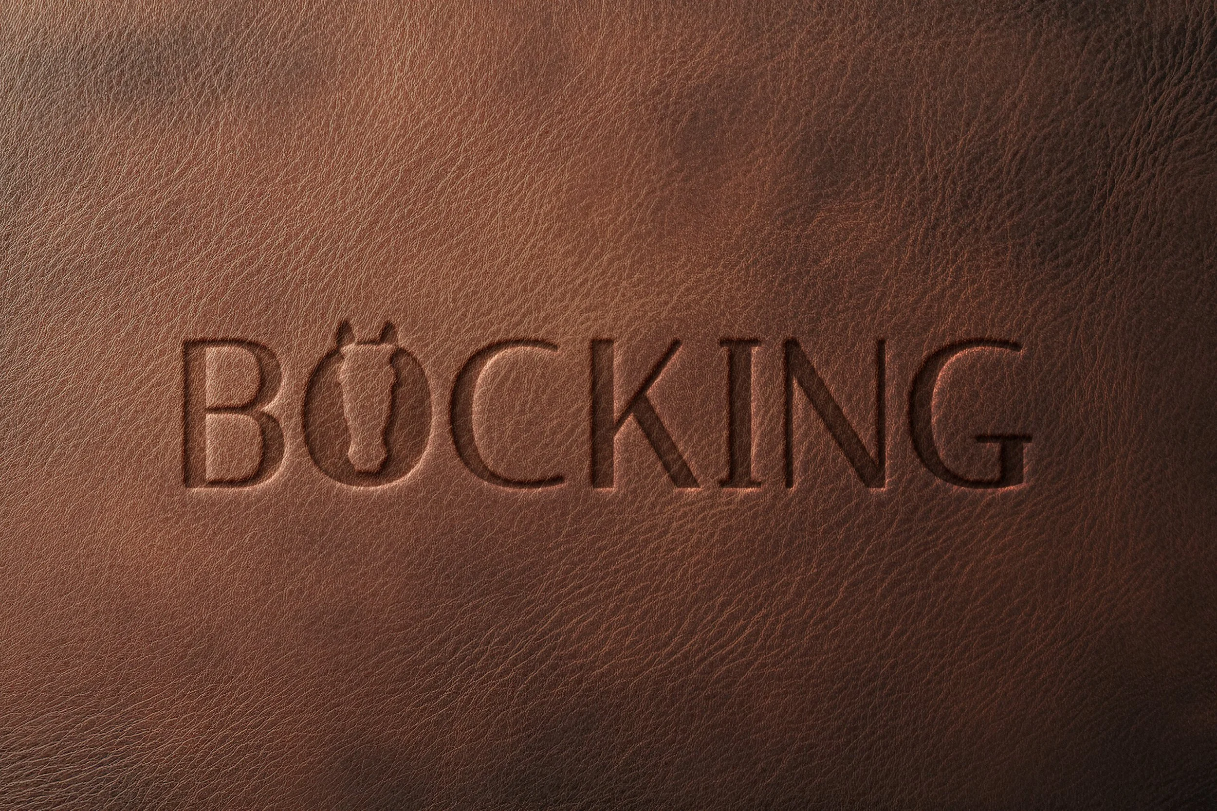 Close-up of brown leather surface with the word 'BOOKING' embossed in it.
