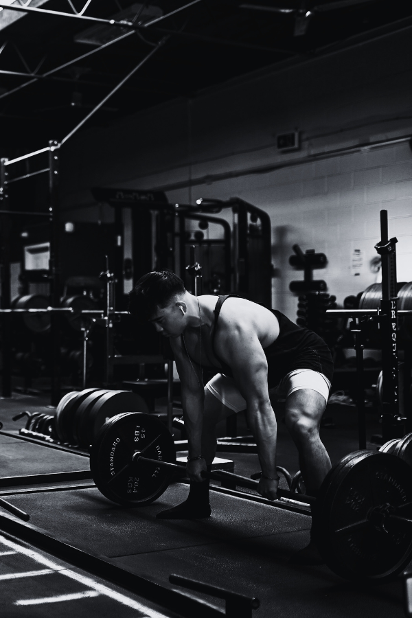 A man lifting weights in a gym, preparing for a deadlift exercise.