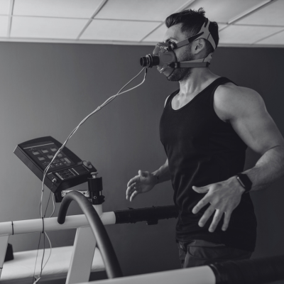 Man running on a treadmill wearing a mask connected to a metabolic testing device.