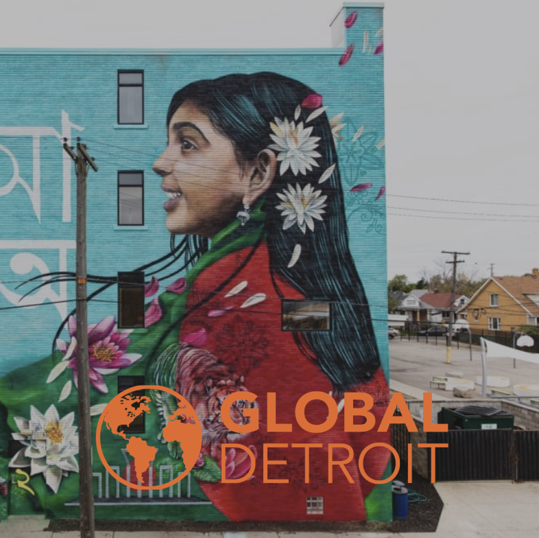 Mural of a woman with dark hair and flowers in her hair on a building wall in Detroit, Michigan, with the words "Global Detroit" and an orange globe logo in front.