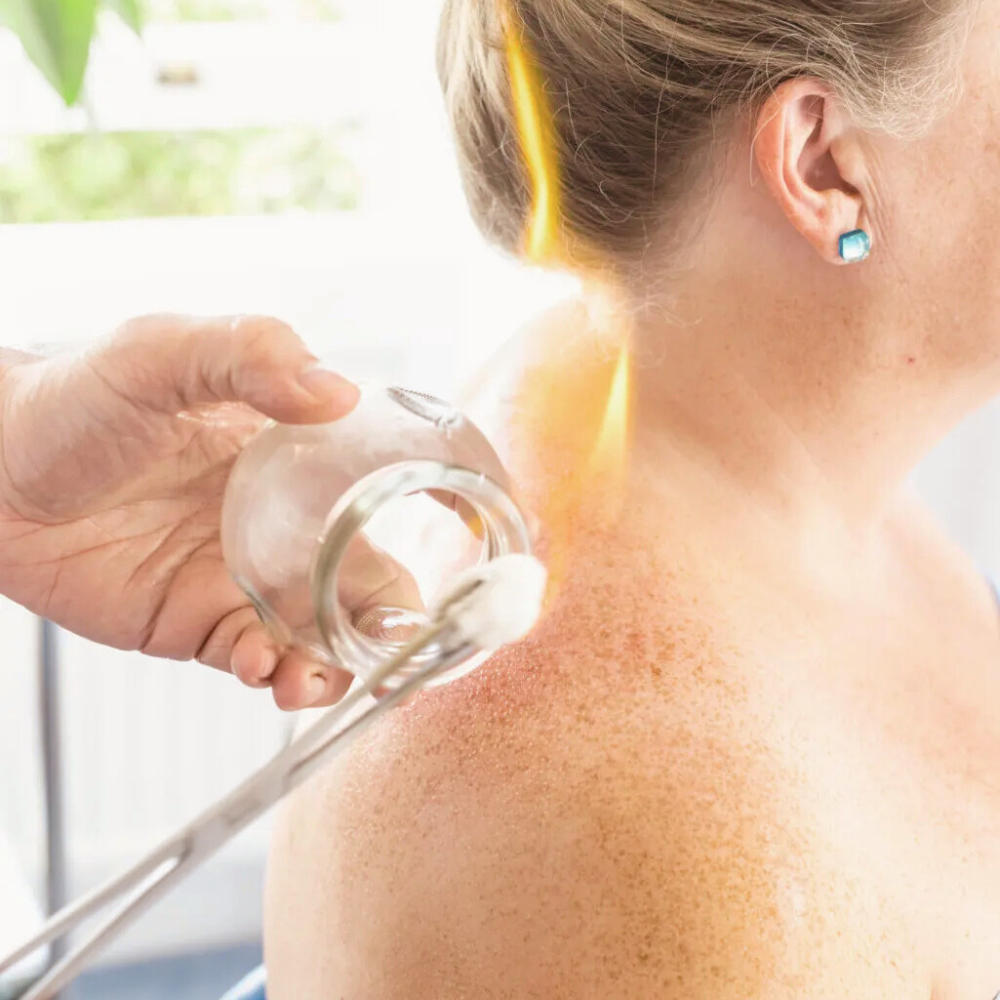 Person receiving a cold compress treatment on their shoulder from a healthcare professional in a clinical setting.