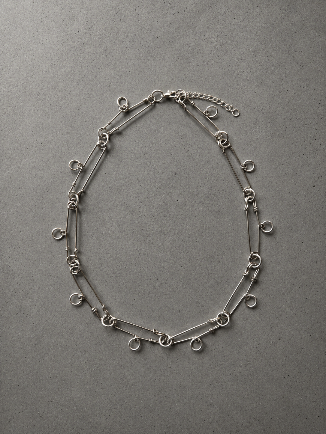 Stainless steel ring necklace with safety pin charms.