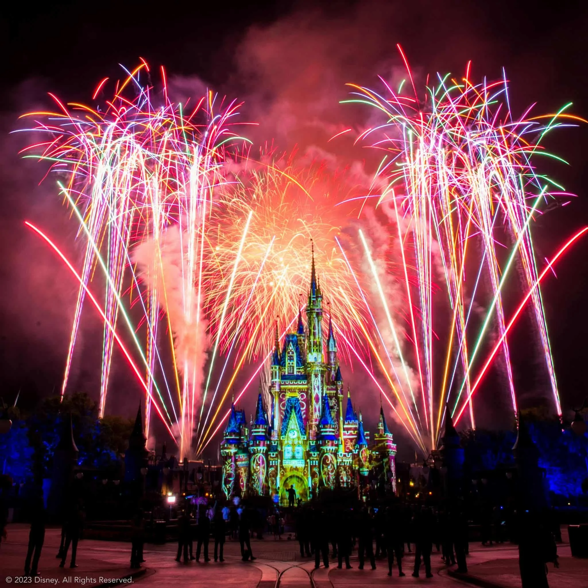 Colorful fireworks exploding over a castle during a nighttime celebration at a Disney theme park.