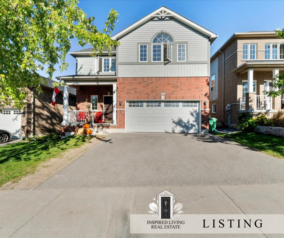 Front view of a two-story house with a brick and grey siding exterior, a two-car garage, and a driveway. There are trees and neighboring houses visible on either side.