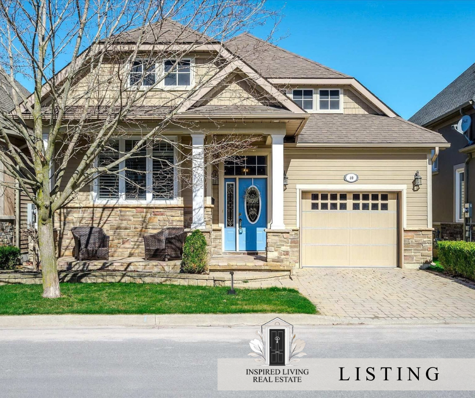 Front exterior of a two-story house with a beige and brick facade, blue front door, two chairs on porch, and attached garage, under a clear blue sky.