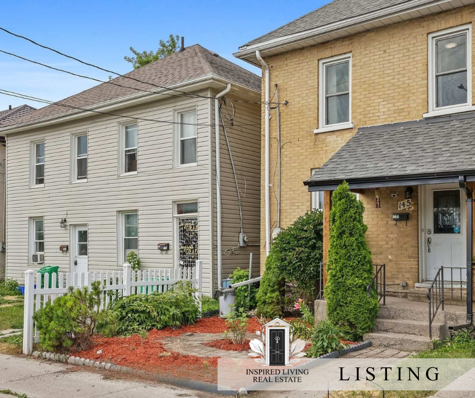 Front view of two attached houses with small front yards, one with white siding and the other with yellow brick, featuring concrete steps, small landscape garden, bushes, and a white picket fence. Clear sky and overhead power lines are visible.