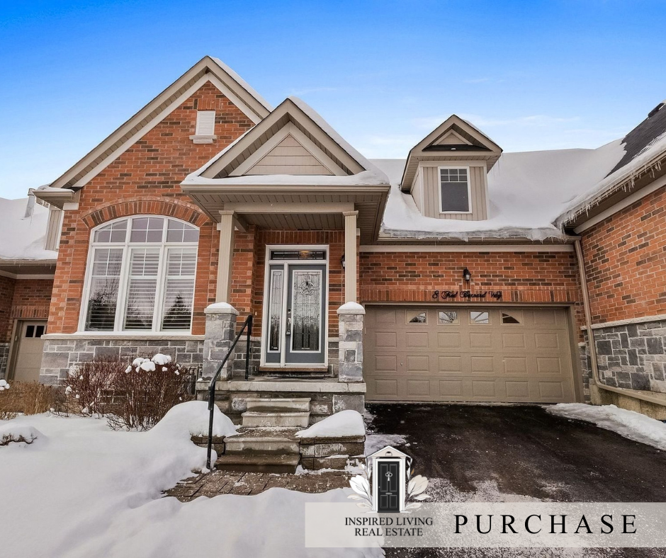 Front view of a brick house with a snow-covered yard, stairs, and driveway, and a garage door under a blue sky.