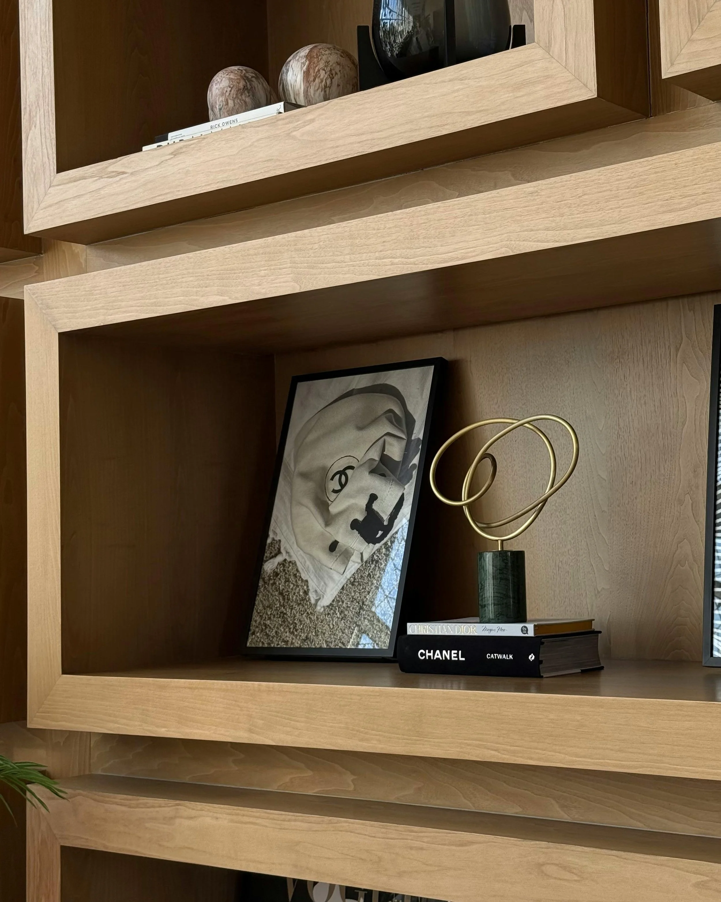 Wooden bookshelf with decorative objects, framed photo, and fashion books.