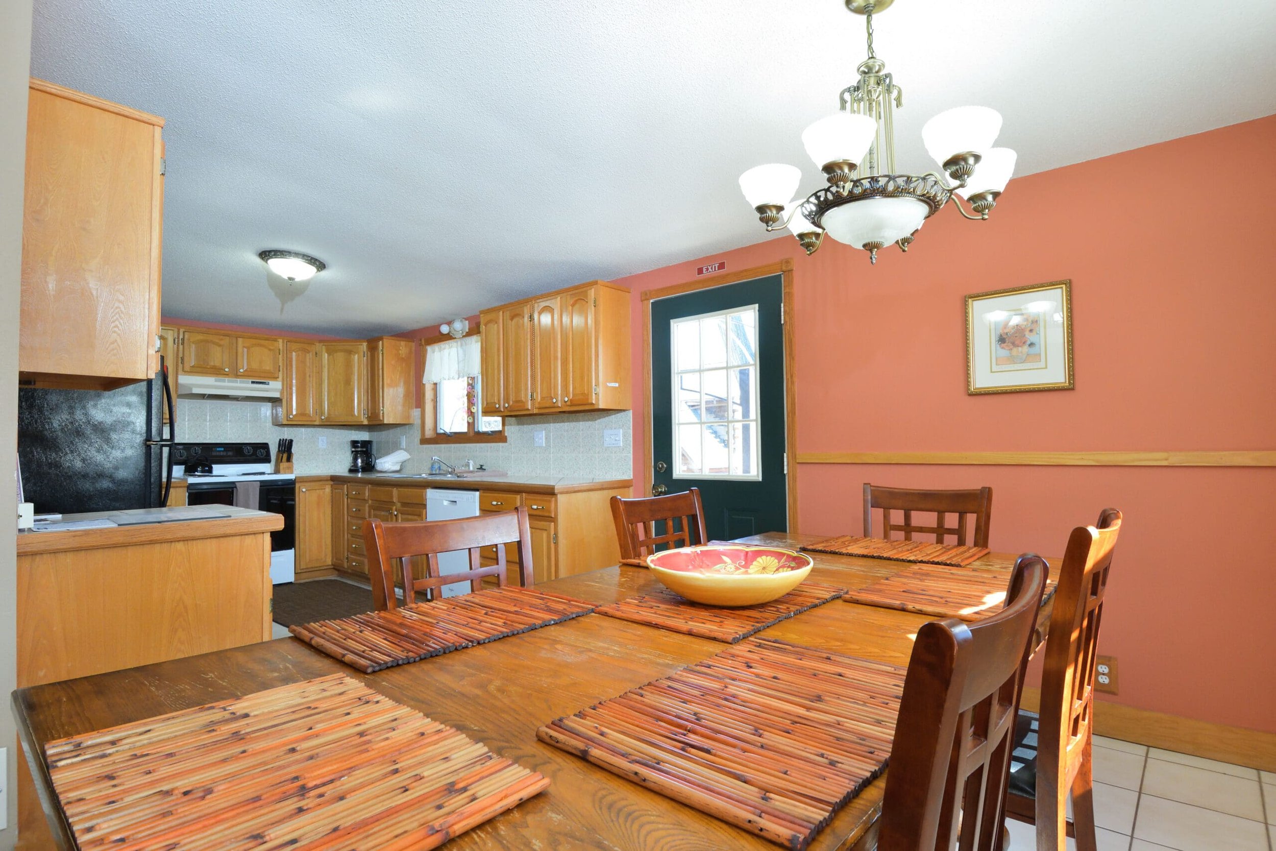 Dining table with placemats and kitchen in background in The Retreat home