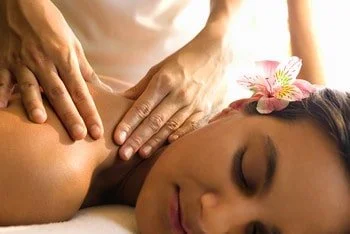 woman with flower in hair receiving shoulder massage