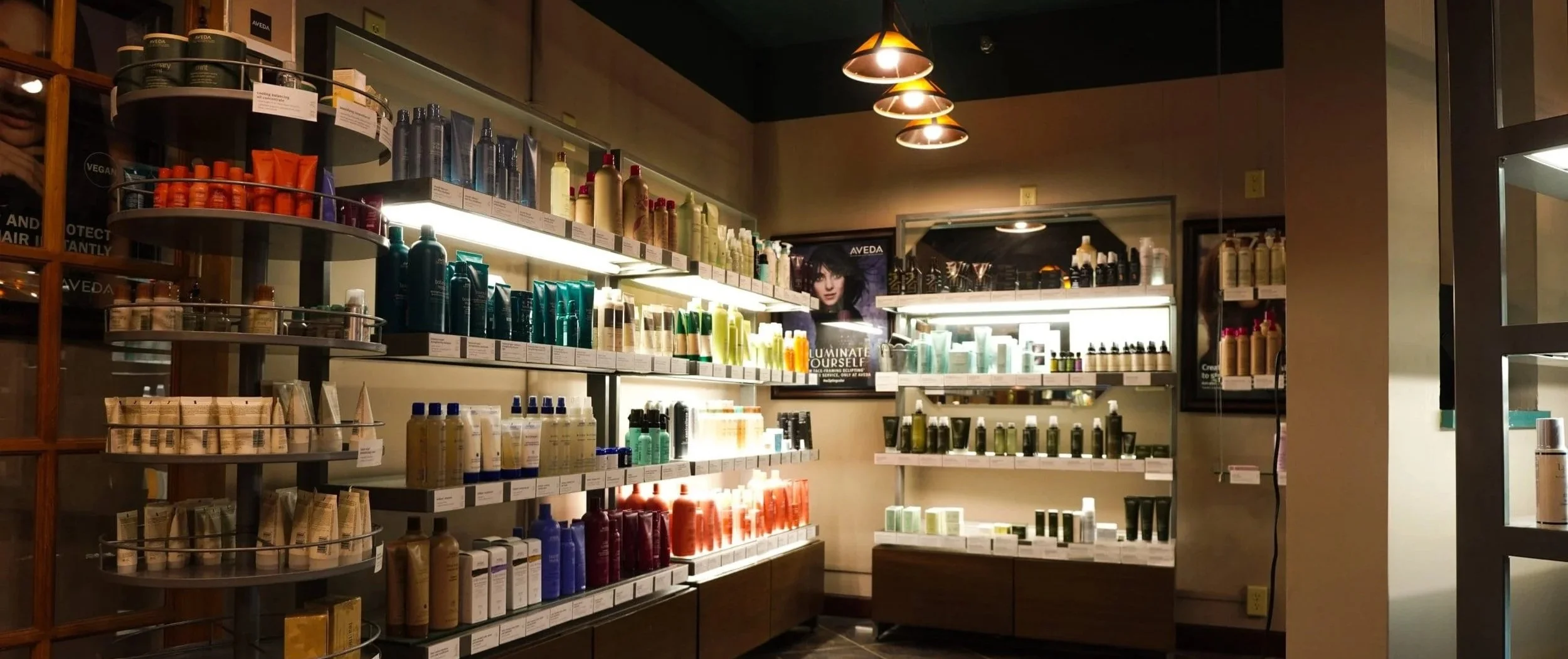 Shelves stocked with various hair and beauty products in a retail store, illuminated by warm overhead lighting.