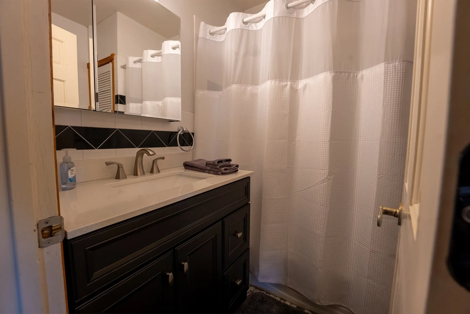 Bathroom with white shower curtain in The Retreat Home