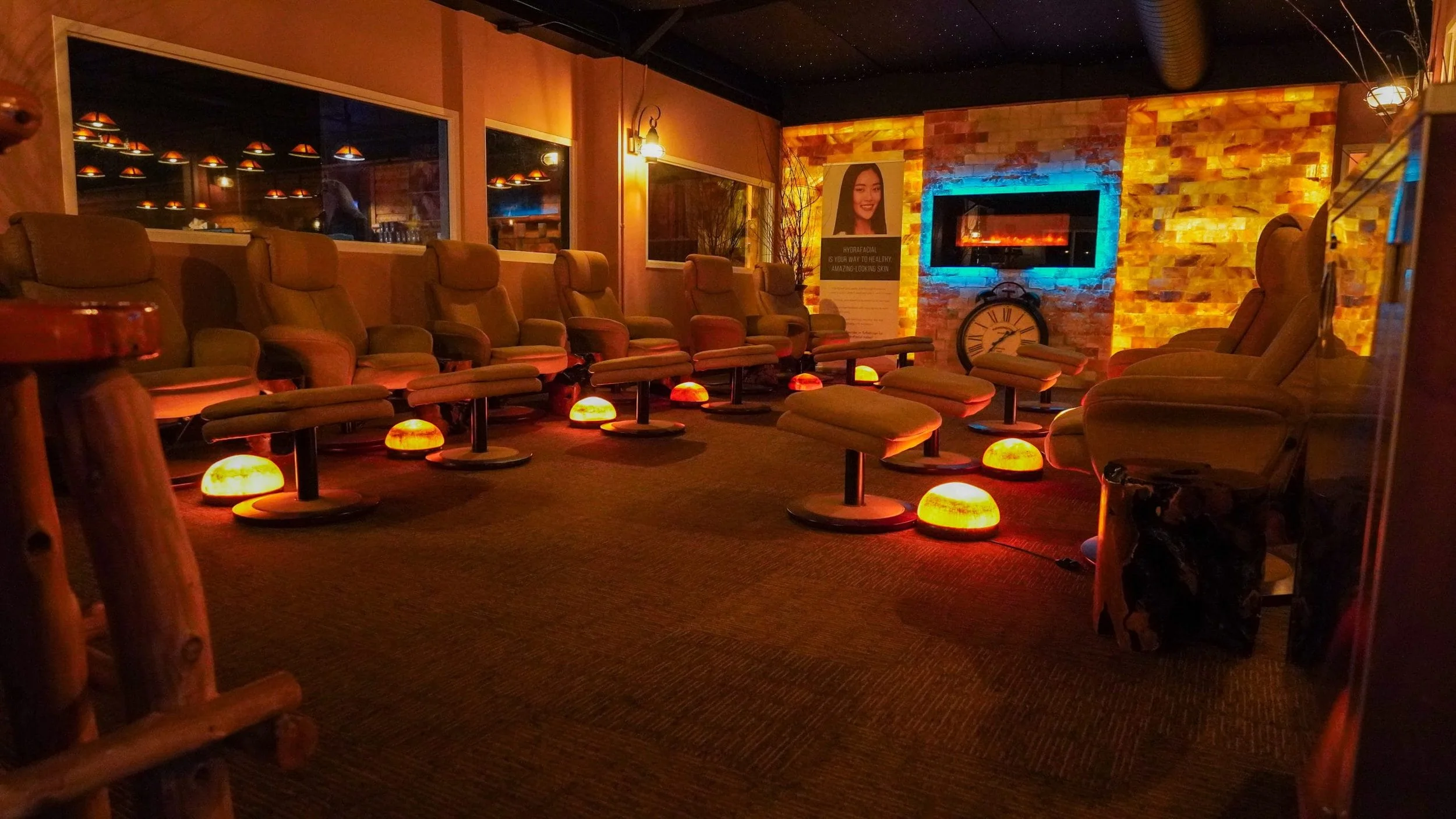 room with several lounge chairs & ottomans, himalayan salt lamps, and fireplace