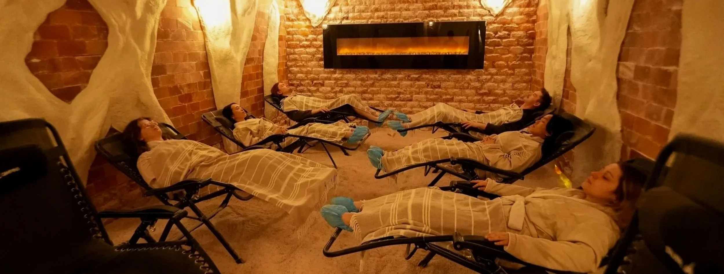 group of people reclined in chairs in salt cave with blankets on