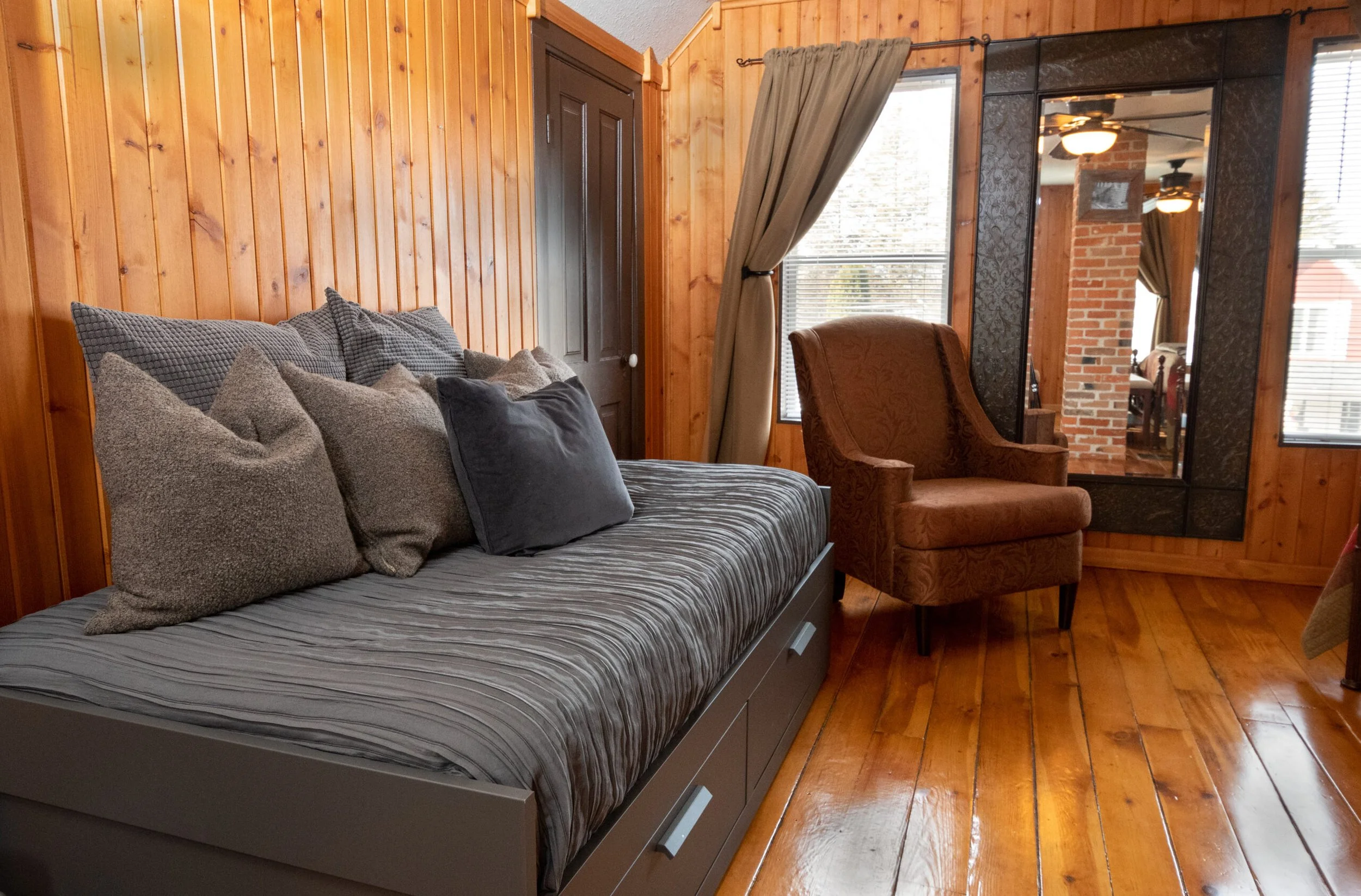 Daybed and upholstered chair in wood-paneled room