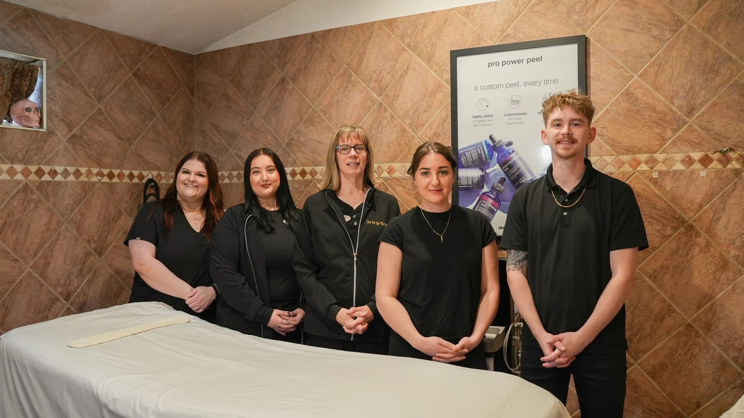 5 team members of Just For Me spa smiling in black shirts