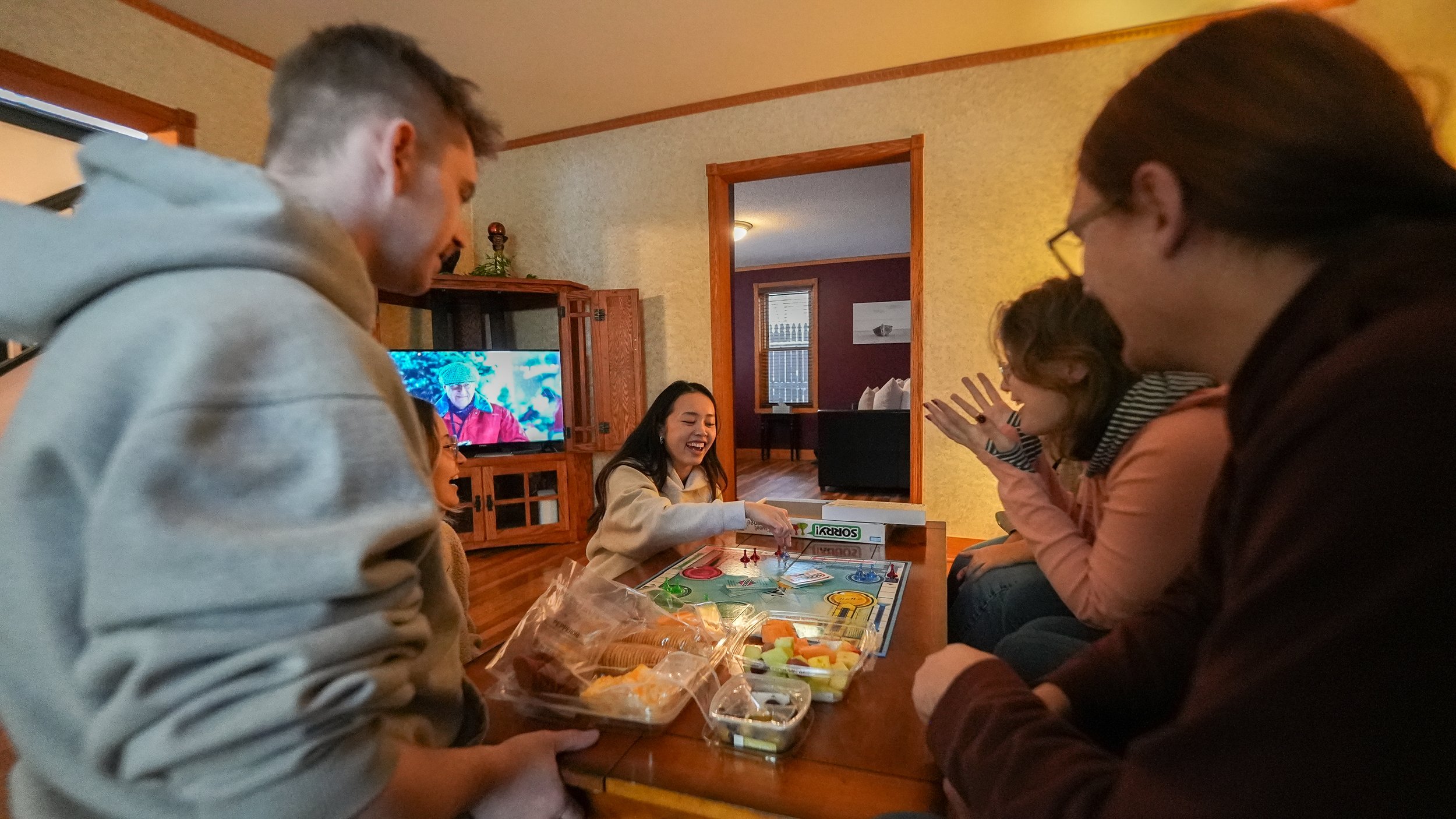 group of people eating snacks at coffee table and watching TV