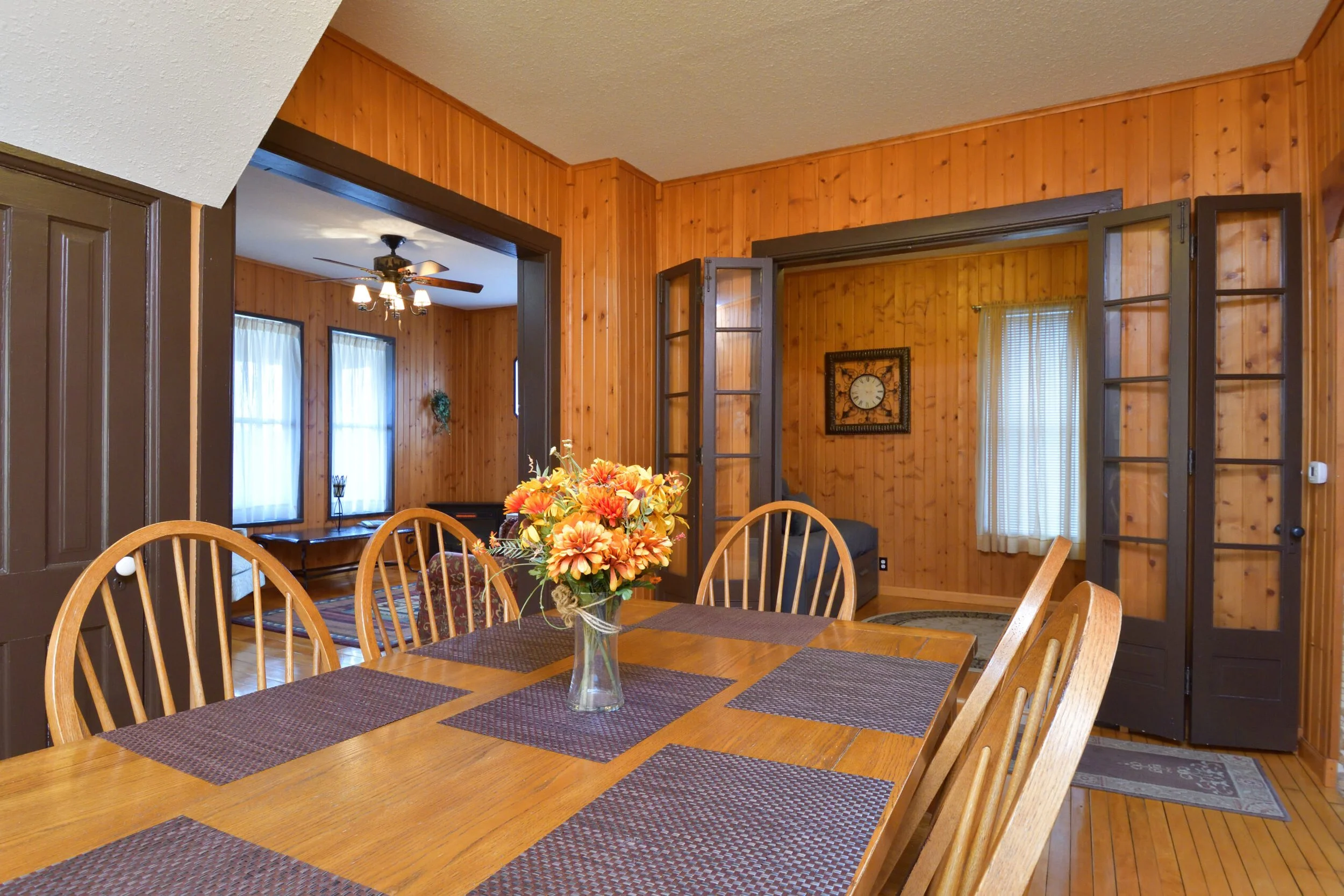 Wooden dining table and chairs in wood-paneled room