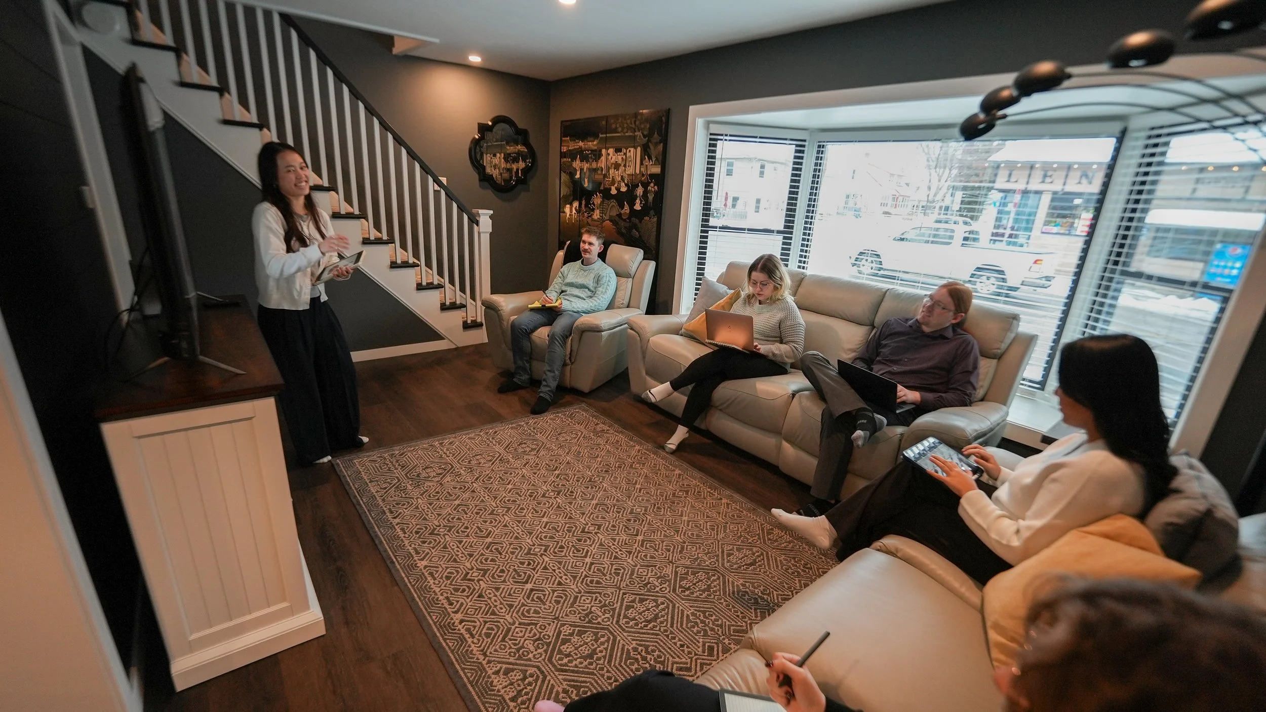 group of people sitting in living room on iPads and laptops