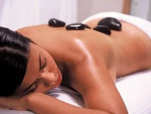woman lying on stomach with hot rocks on back