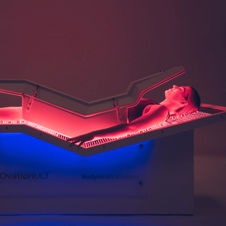 woman laying in infrared light therapy bed in the dark