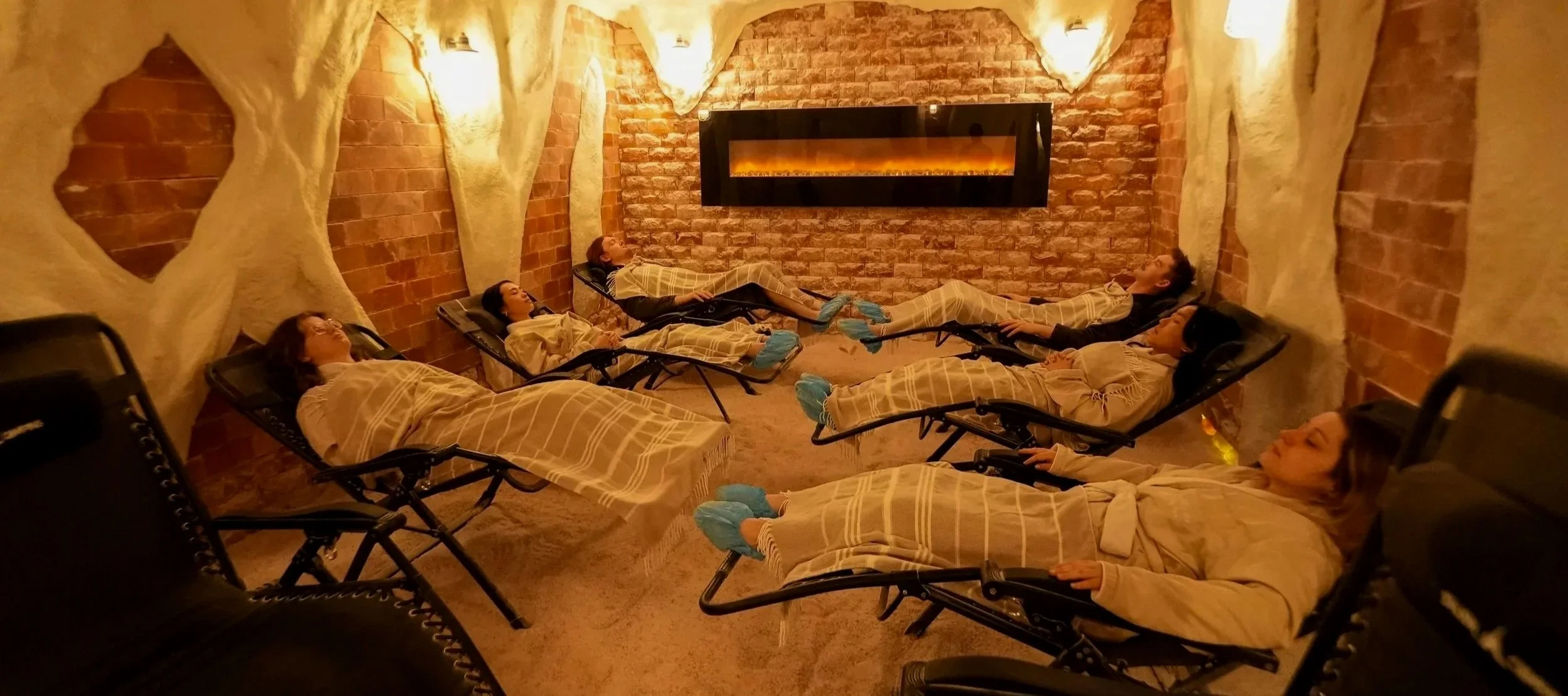 group of people reclined in chairs in salt cave with blankets on