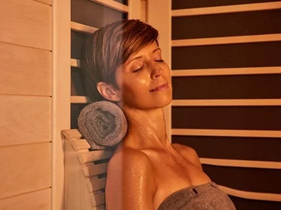 woman relaxing in sauna with towel rolled up behind neck
