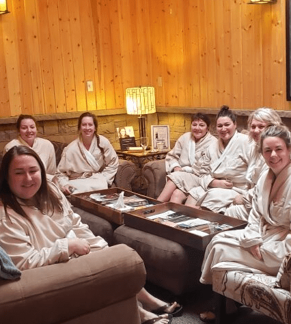 group of women sitting in robes and smiling at spa