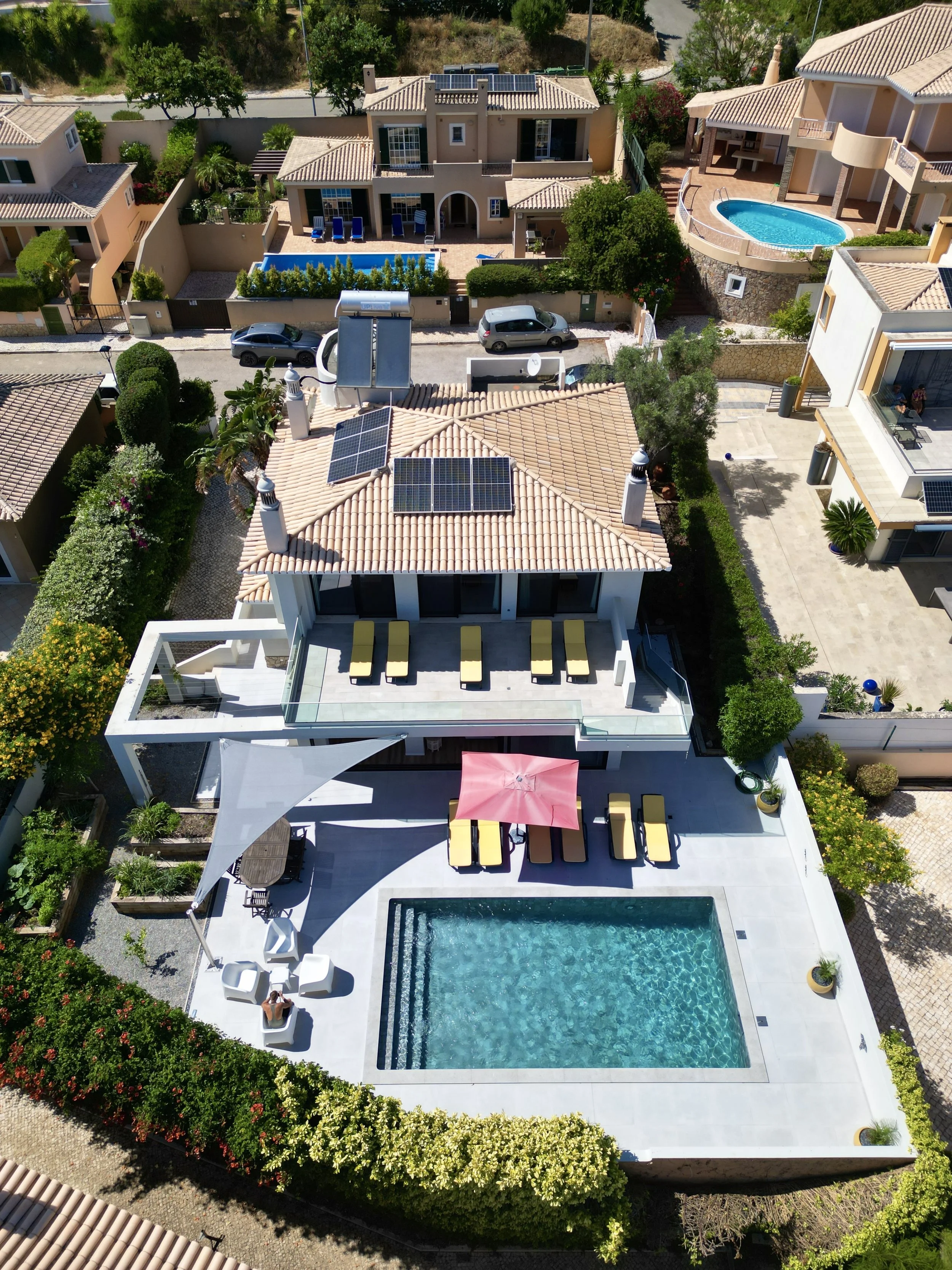 Aerial view of a modern residential property with a backyard, swimming pool, outdoor seating, and neighboring houses.