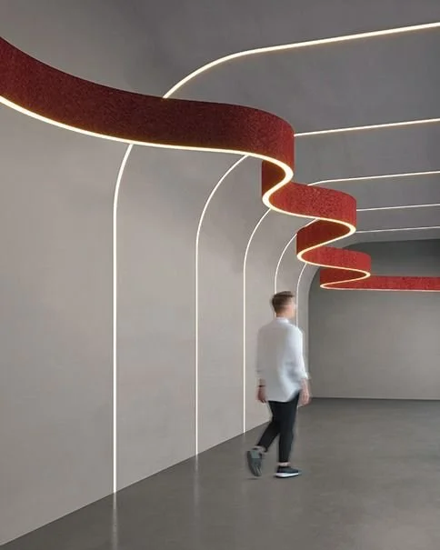 Innenraum mit modernen, geschwungenen roten und weißen Beleuchtungsleisten an der Decke, eine Person läuft durch den Raum.
