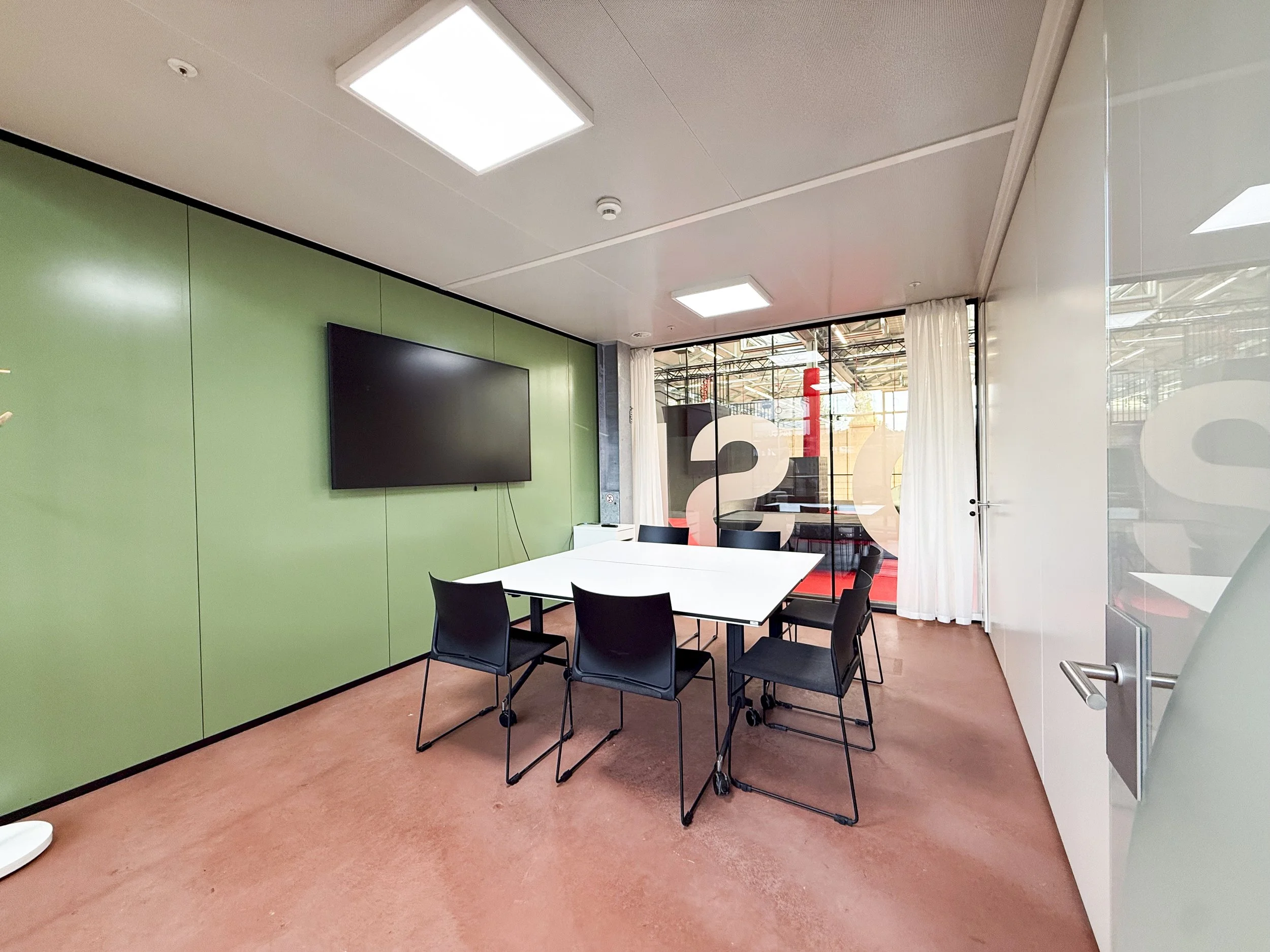 Moderner Konferenzraum mit weißem Tisch, weißen Stühlen auf Rollen, Wandpaneelen aus Holz, TV an der Holzwand, blauer akustischer Decke mit modernen Lichterleuchten.