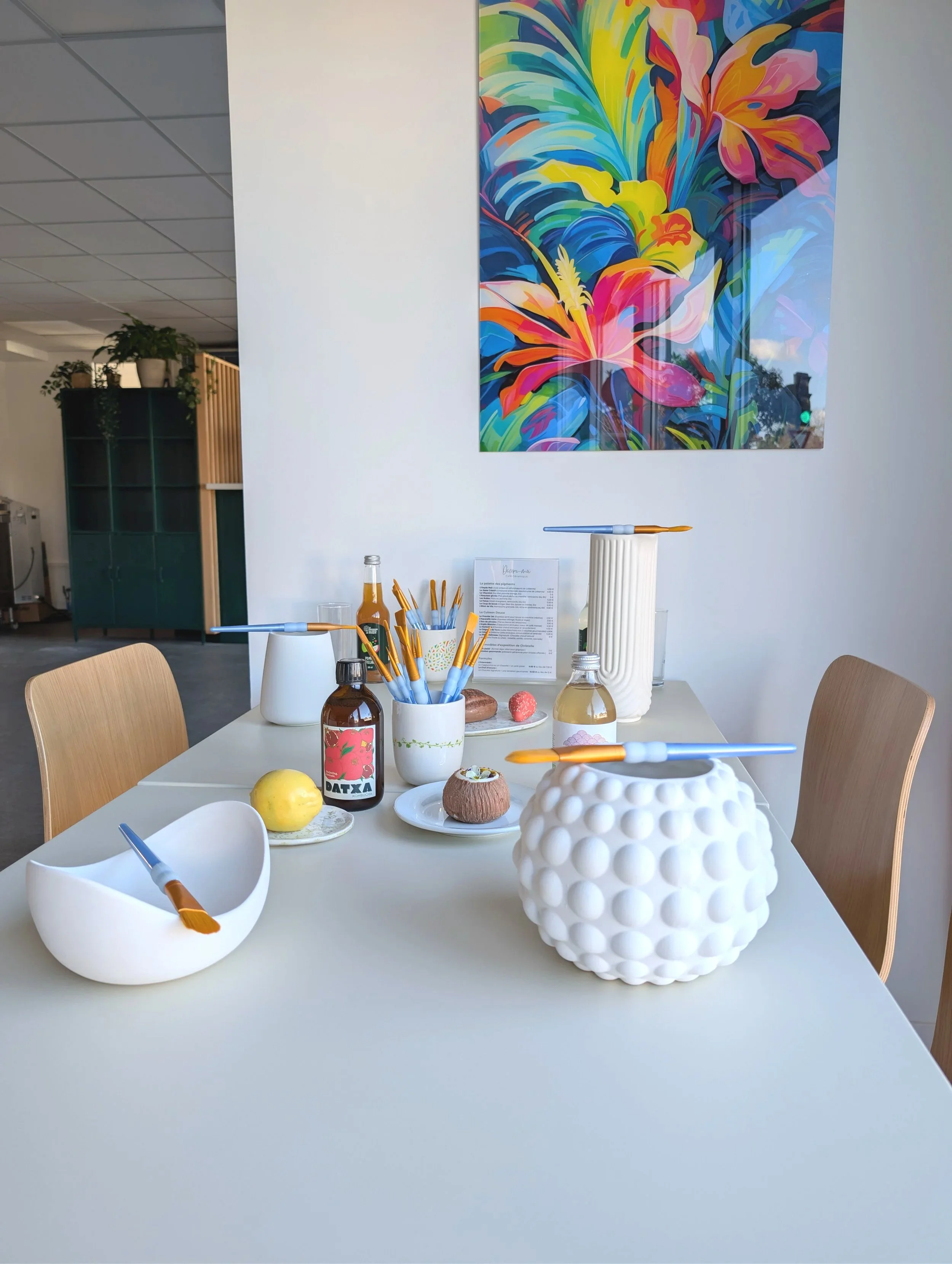 Table du café céramique Décore-moi à Labenne avec un bol nid et un vase bubble, une boisson fraîche, des pâtisseries trompe l'oeil en forme de fruits et un tableau moderne et coloré pour une décoration de goût.