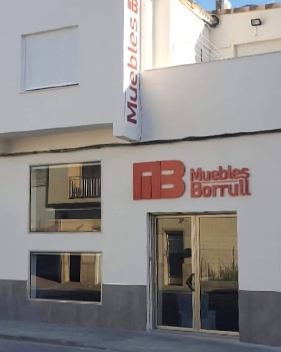 Exterior of a white building with a sign that reads "Muebles Borrull" in Spanish, indicating a furniture store.