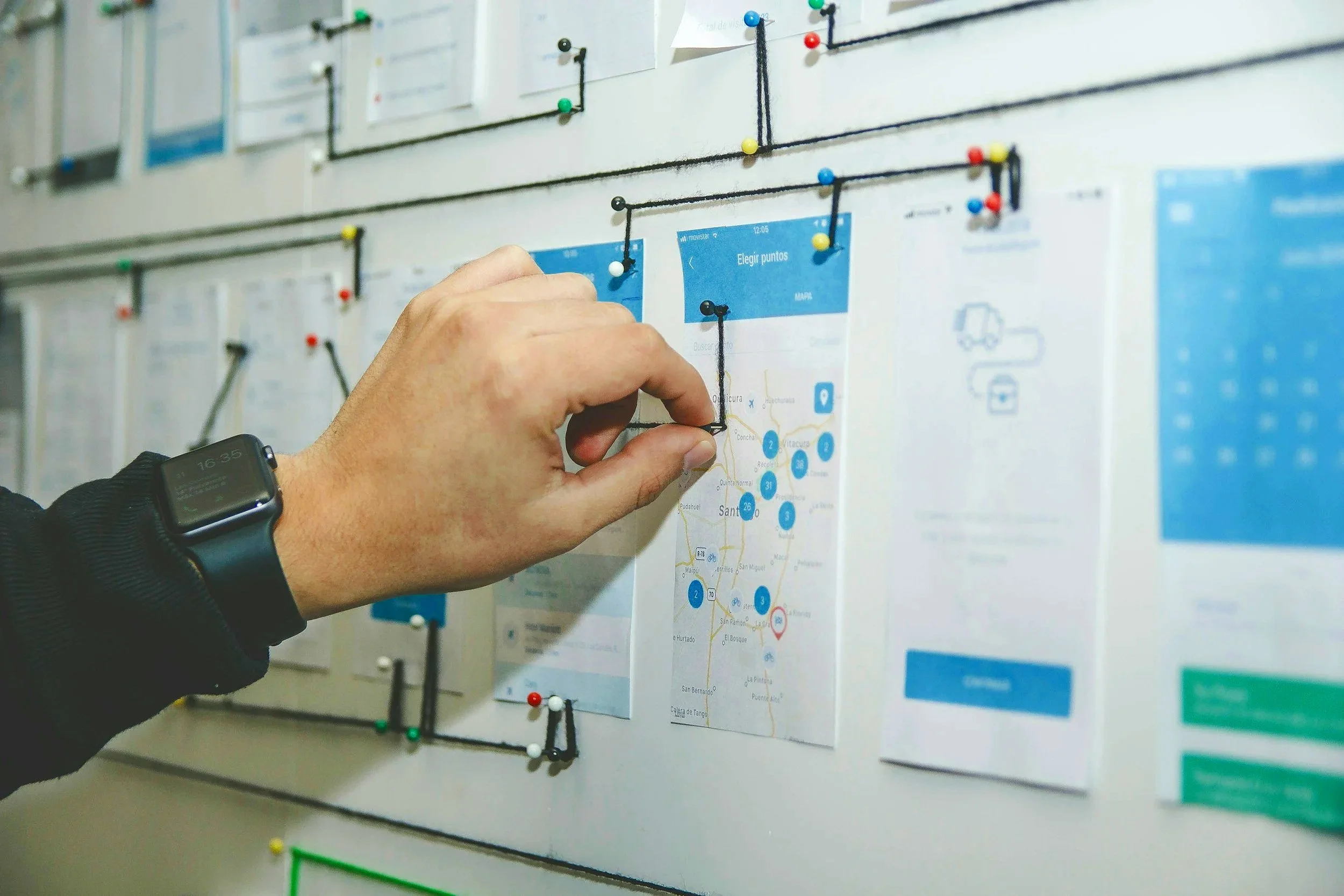 Une personne ajuste un plan de métro sur un tableau blanc avec des épingles colorées.