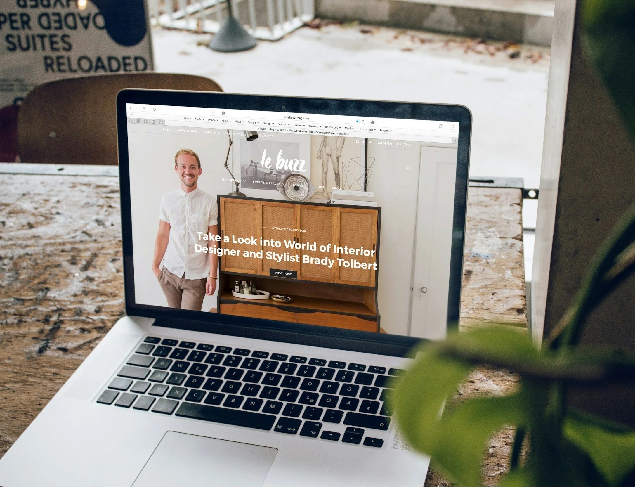 Capture d'écran d'un site web sur un ordinateur portable, mettant en avant un homme souriant, avec des meubles de design intérieur, dans un intérieur moderne.