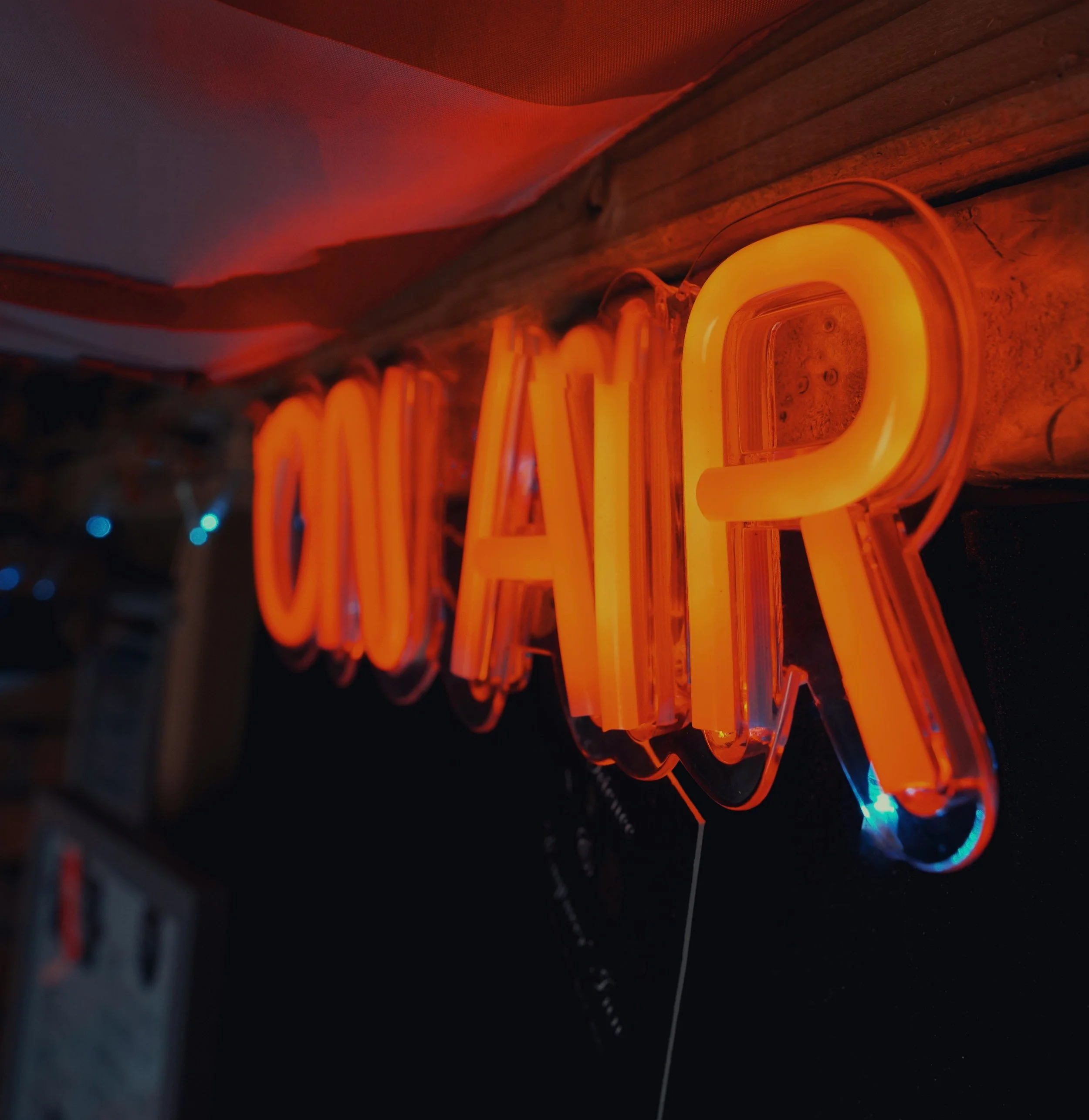 Close-up of a bright orange neon sign that reads 'COFFEE' mounted on a wooden wall.
