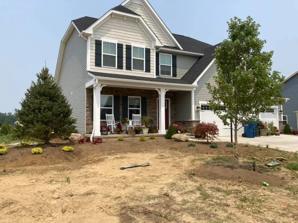 Front view of a two-story house with a front porch, lawn, and trees.