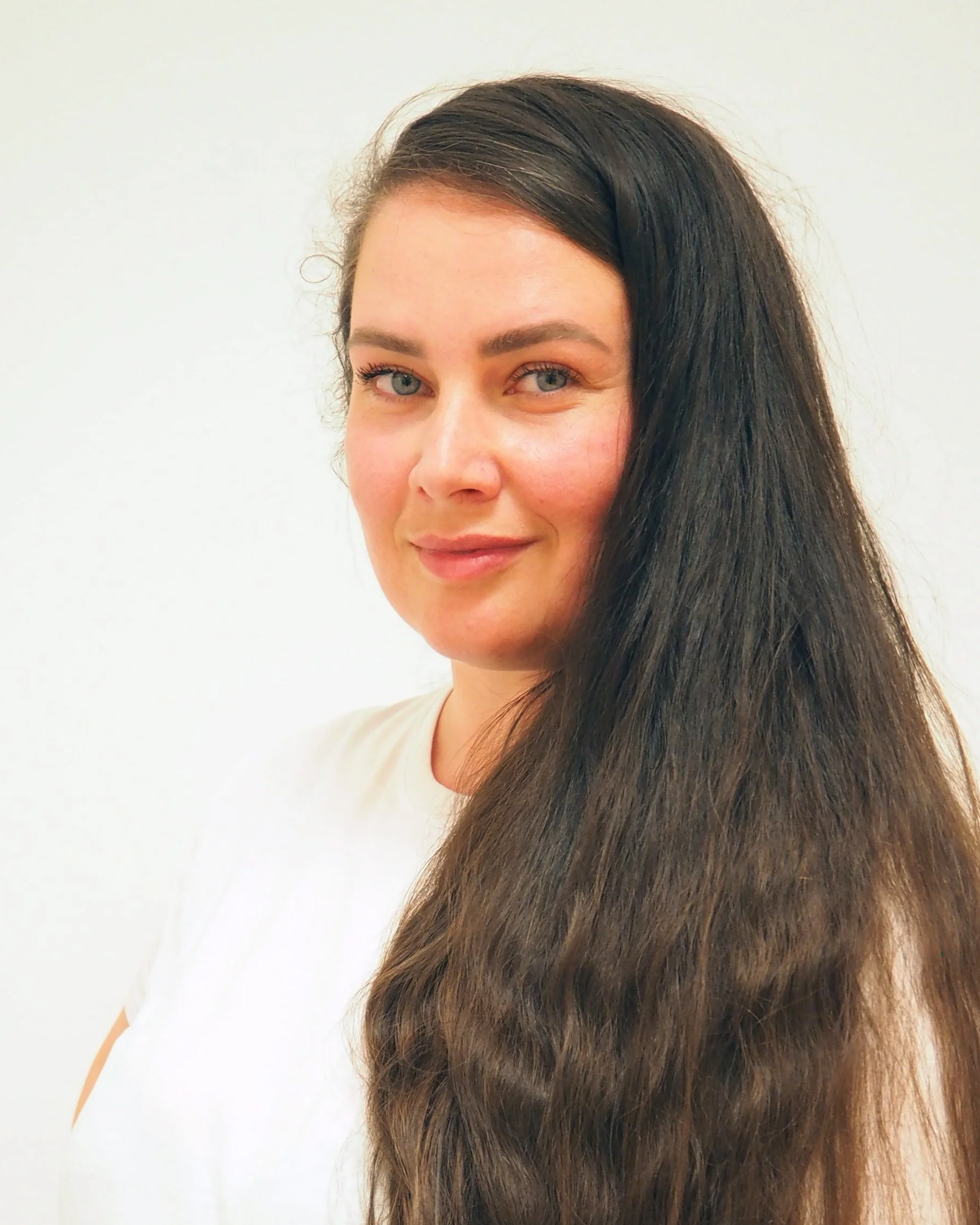 Nahaufnahme einer Frau mit langen, dunkelbraunen Haaren und blauen Augen, lächelnd vor weißem Hintergrund. Die Frau ist Cristina-Tatiana Boldea BSc. Physiotherapeutin.