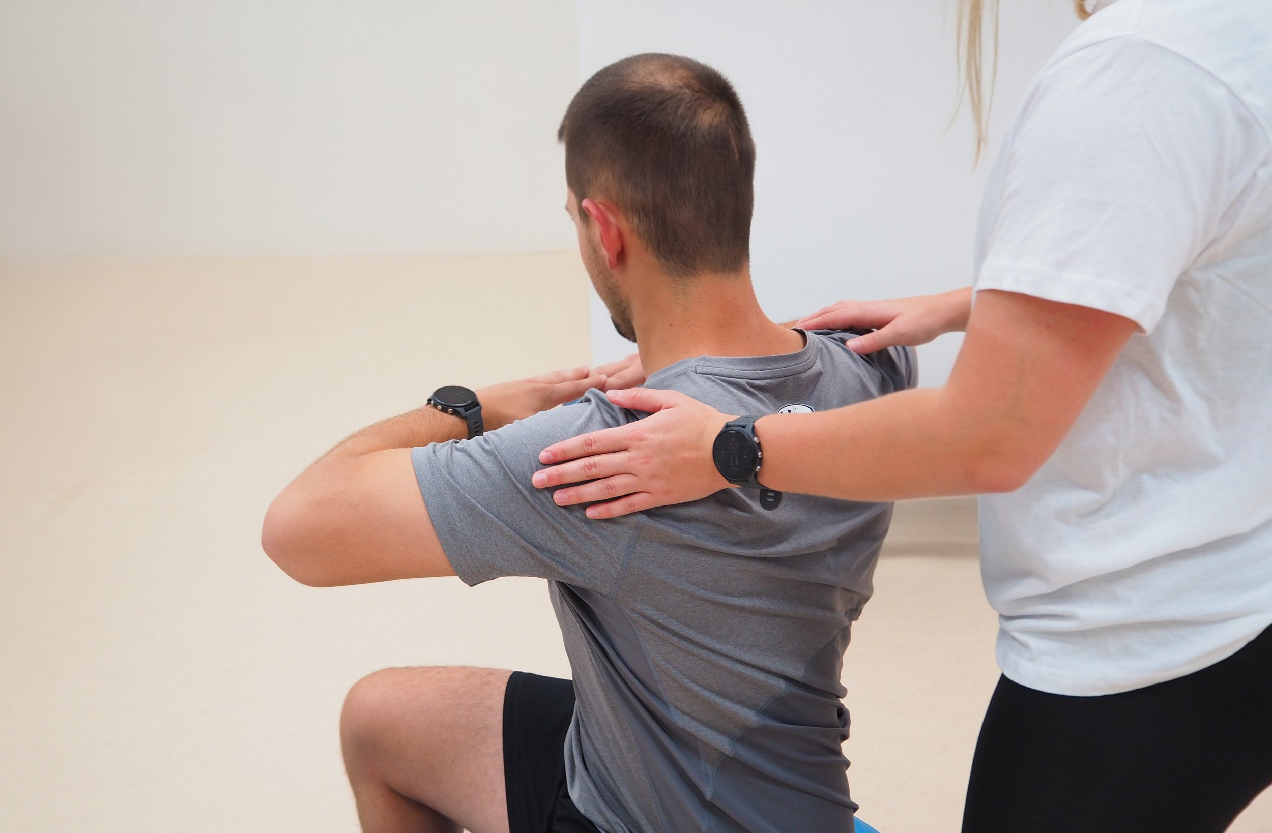 Mann macht Yoga-Übung mit Unterstützung einer Therapeutin in einer Praxis.