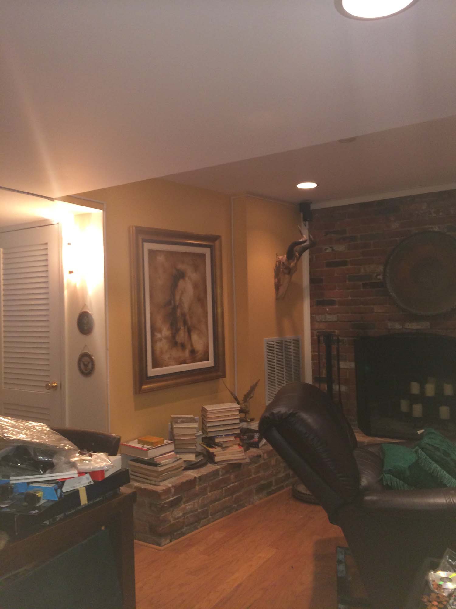 Living room with brick fireplace, leather chair, and stacks of books on a brick ledge.