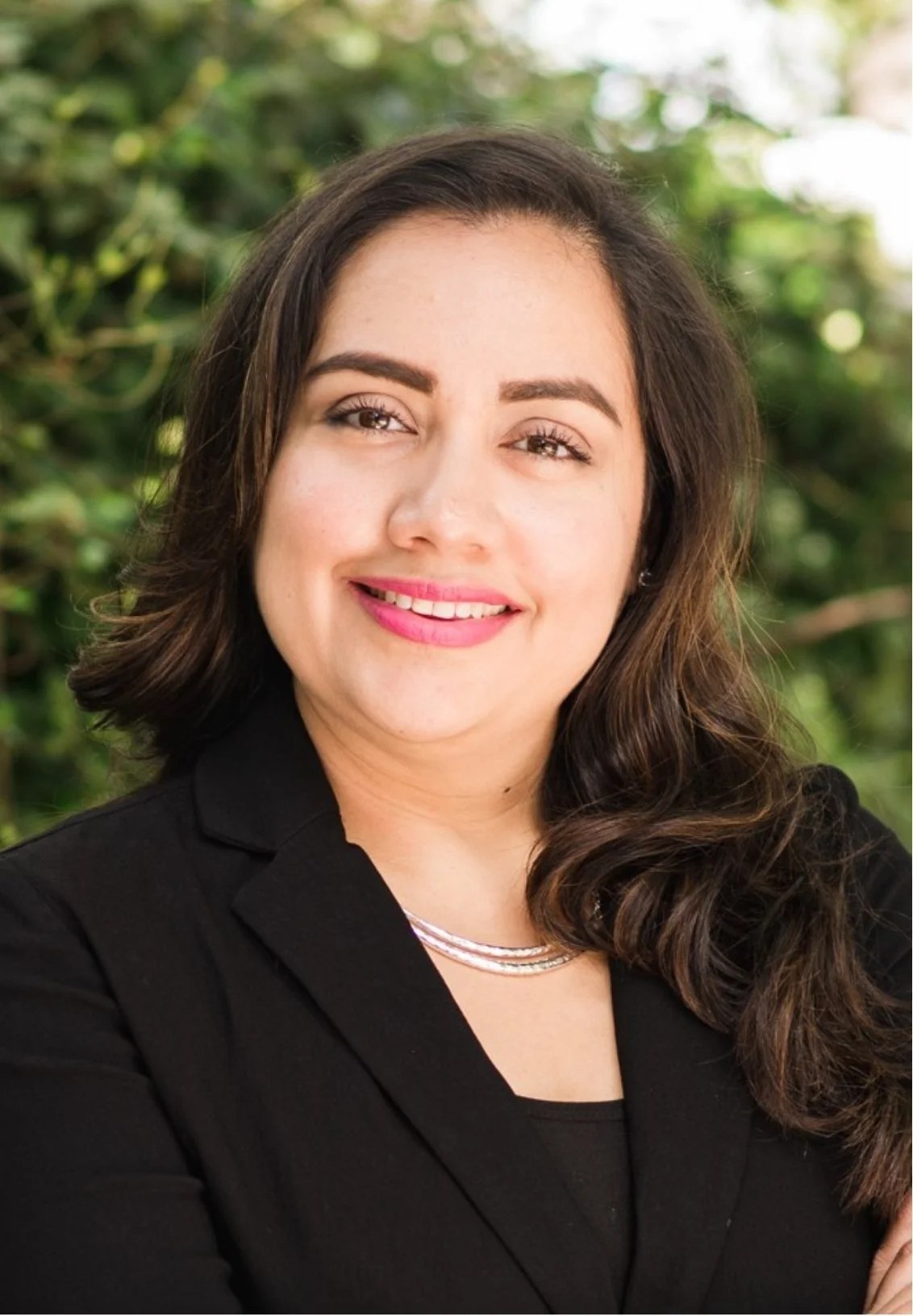 Katy TX therapist Lizet Orozco smiling with pink lipstick, wearing a black blazer and layered necklaces.