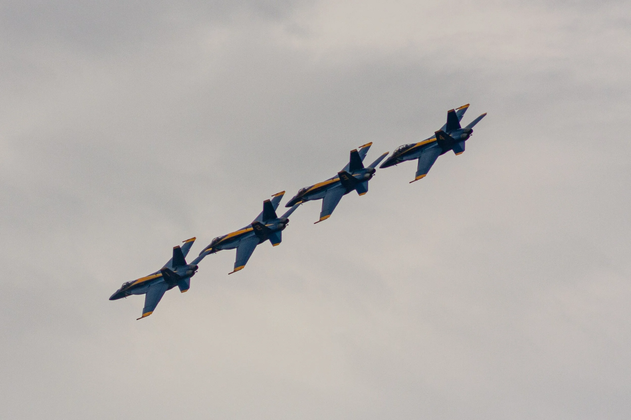 Four Blue Angels aircraft fly in a precise diagonal line.