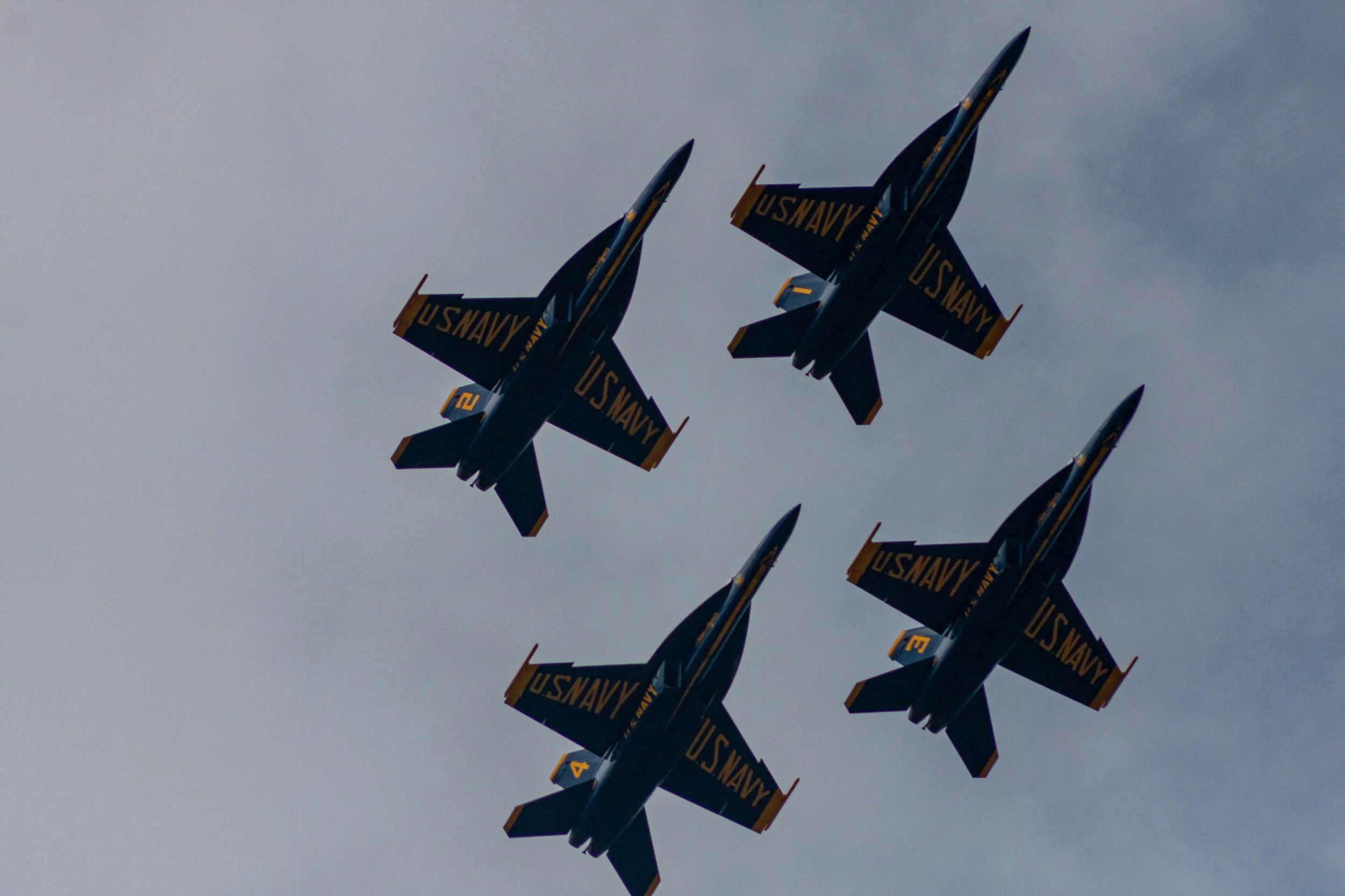 Four Blue Angels aircraft pass overhead in tight formation.