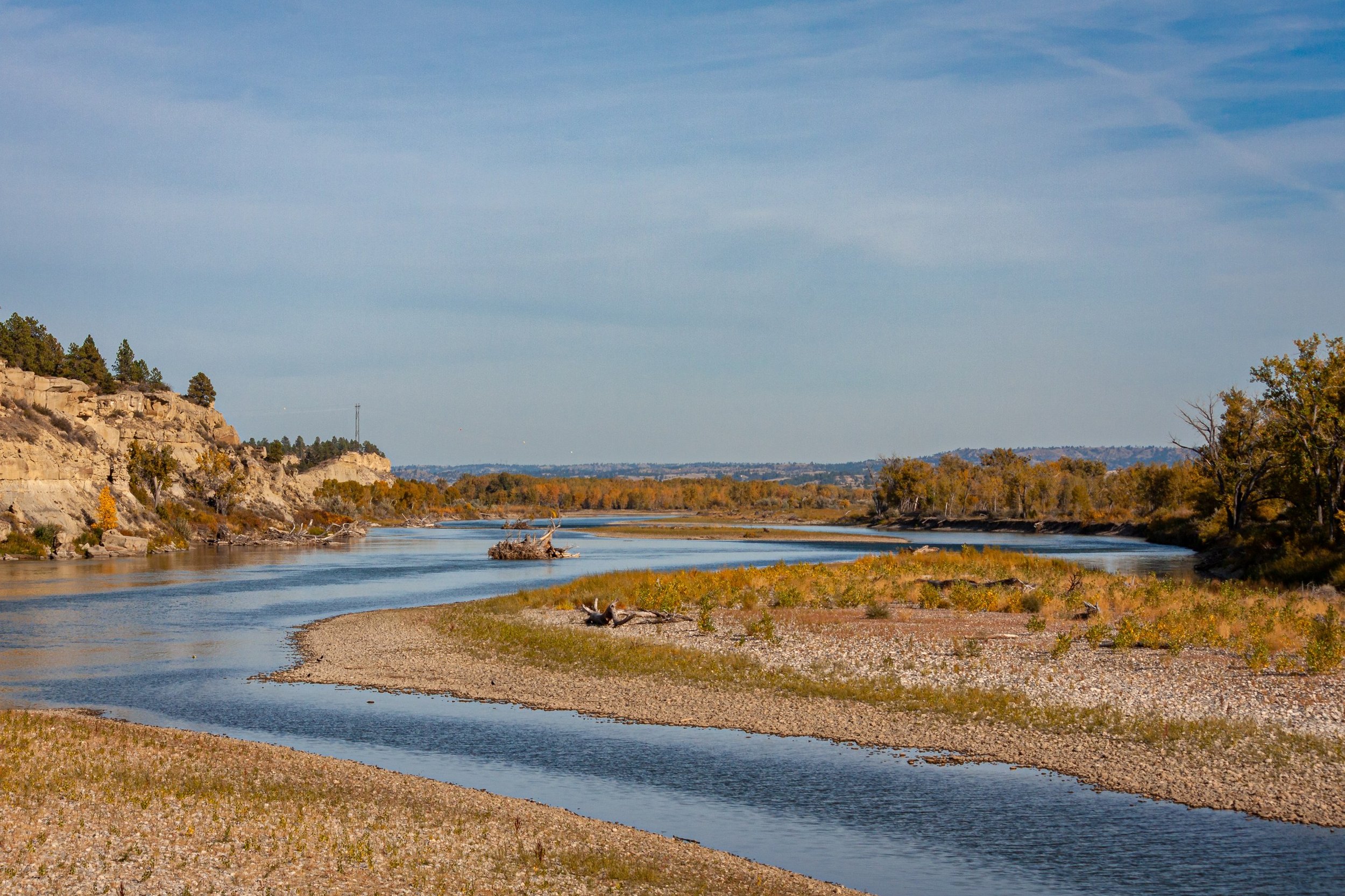 A river curves through autumn grasses and low sandy banks.