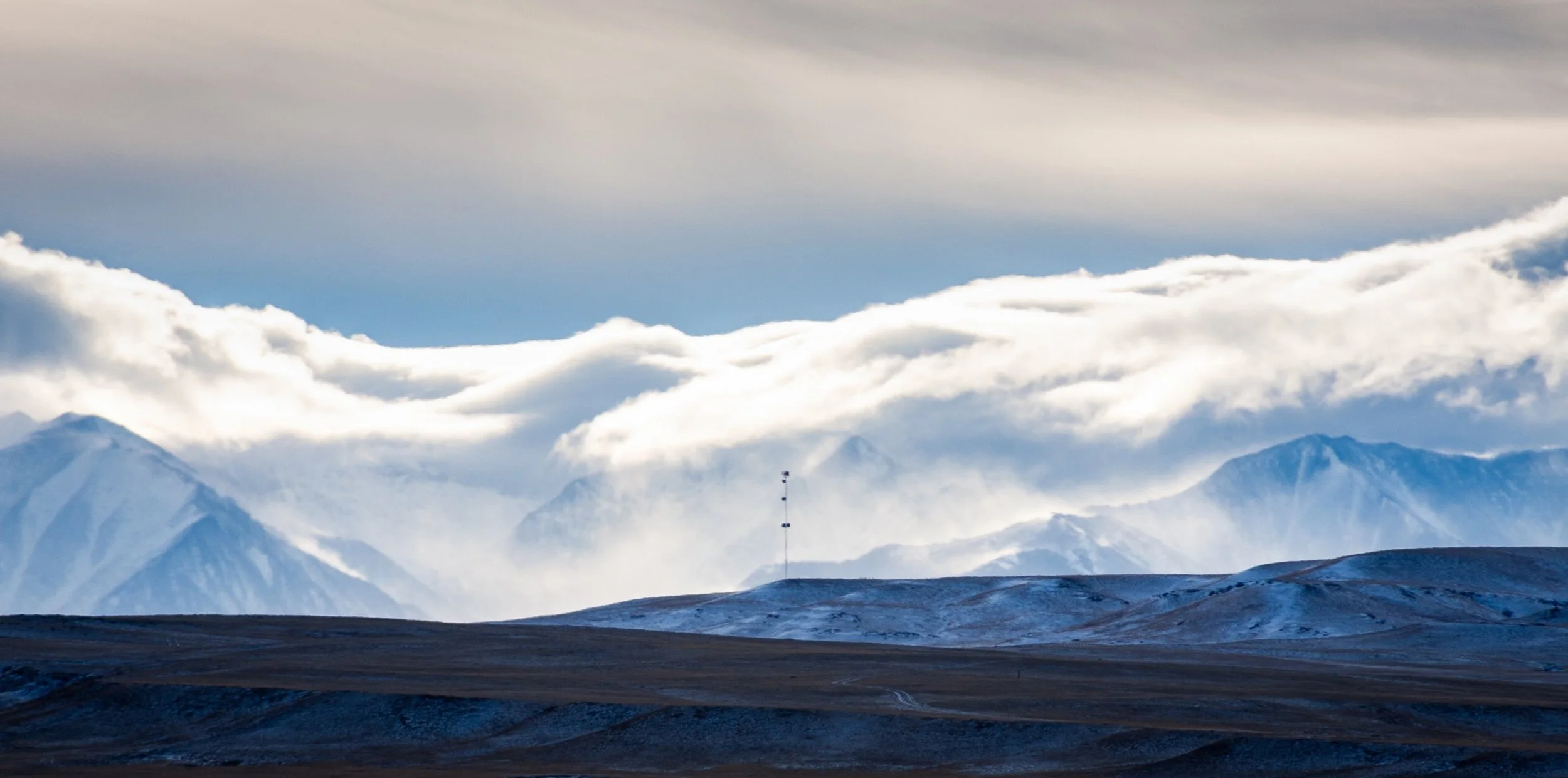 Sunlight breaks through storm clouds above mountain ridges.
