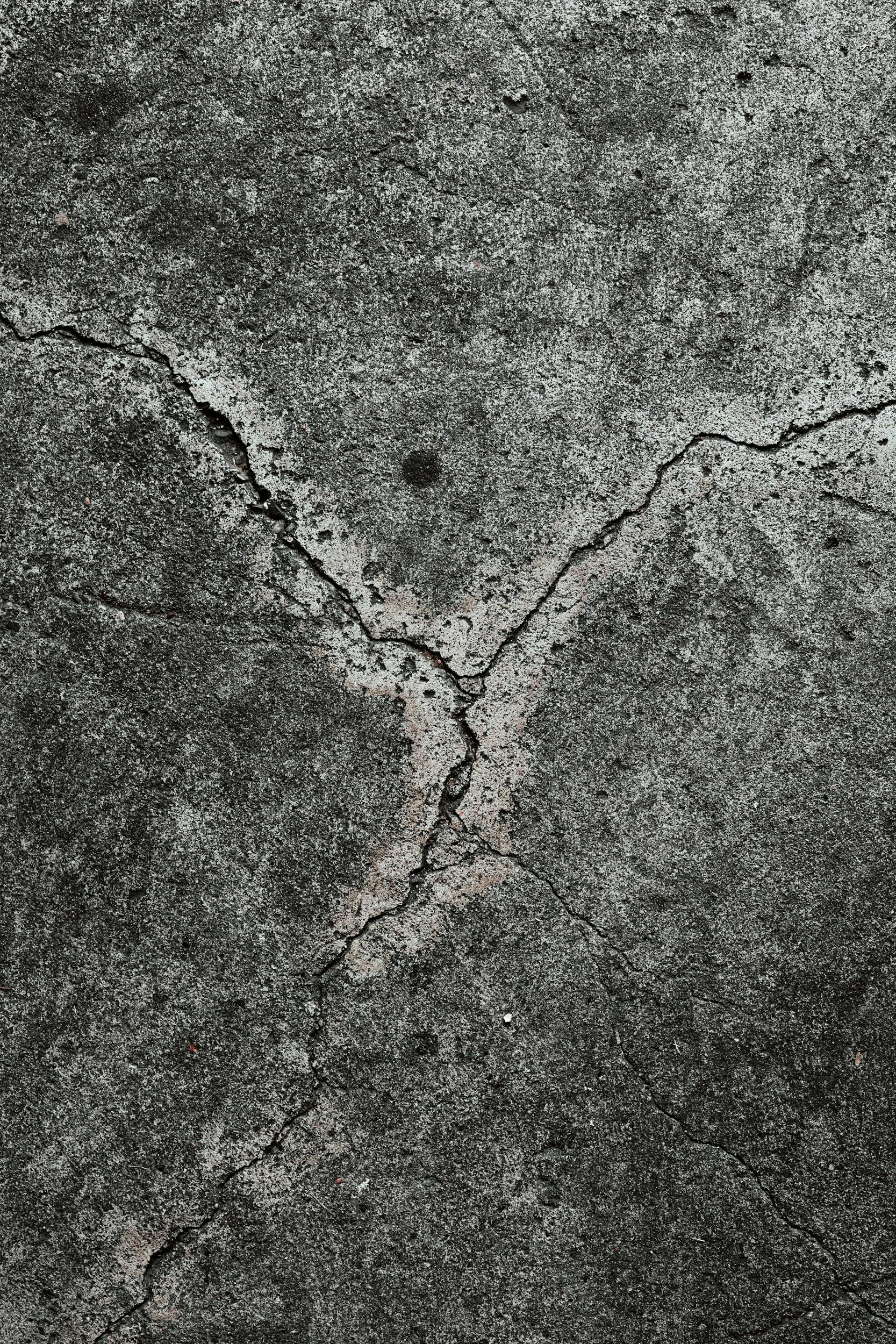 Close-up of a cracked dark gray concrete surface.